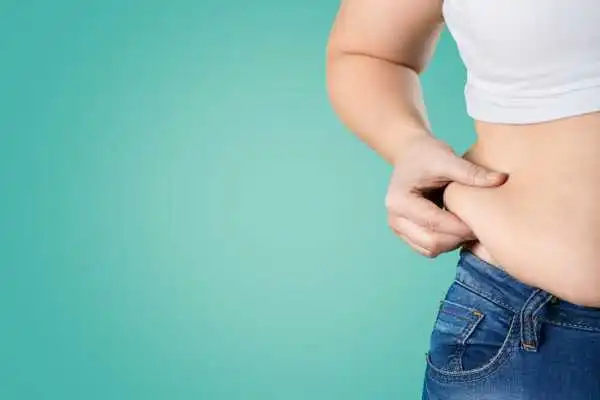 Image of woman pinching her love handles to show weight gain Sparkhill