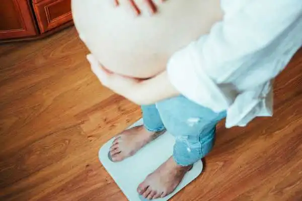Image of woman weighing herself and experiencing weight gain through pregnancy Sparkhill